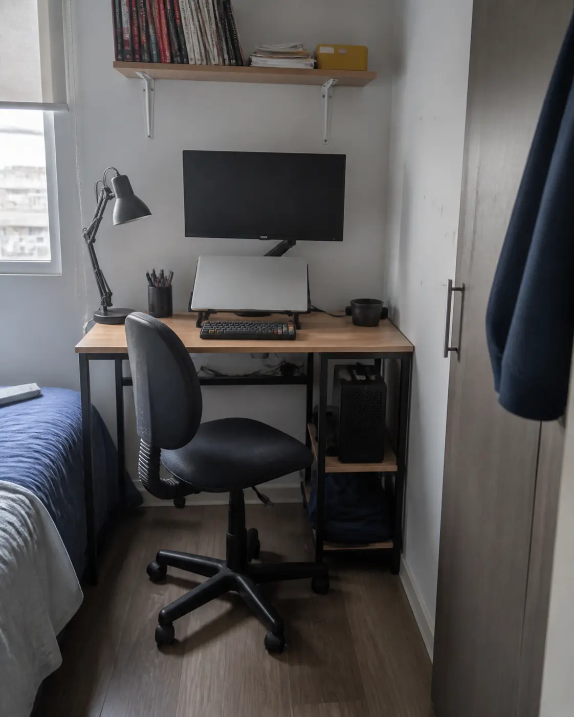Setup compacto con monitor, notebook y computador en un rincón estrecho de dormitorio
